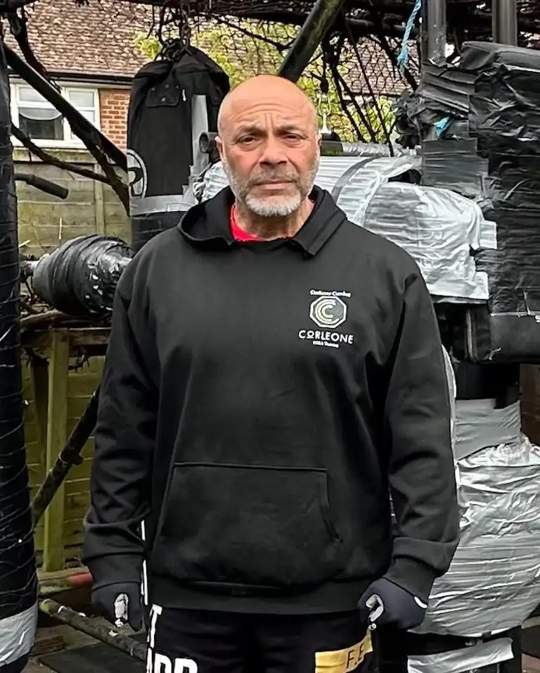 Carlito standing outdoors in front of punch bags and boxing equipment