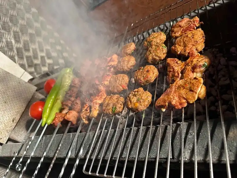 Slow-smoked meat cooking on a grill at the Corleone BBQ Shack